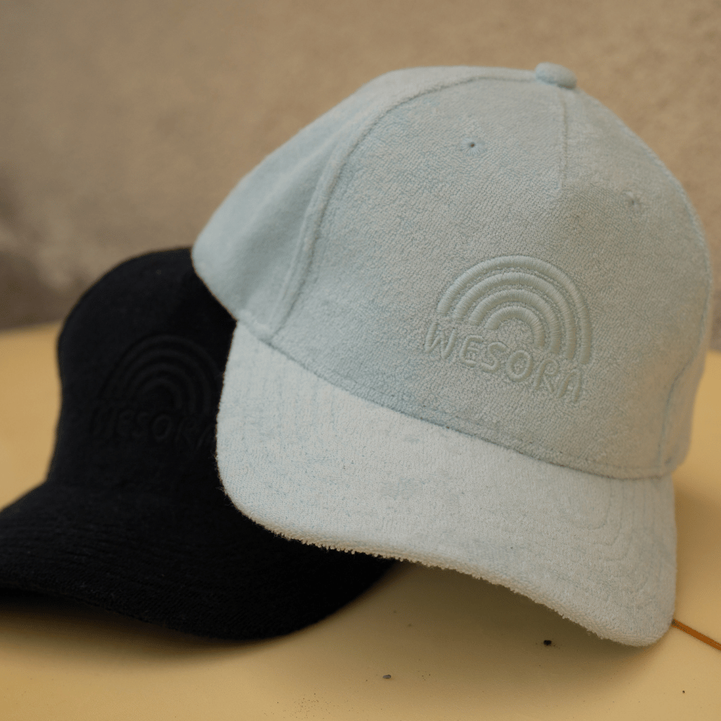 Frottee Cap - All Black & Fresh Mint mit minimalistischem Design und Ton-in-Ton Stickerei, liegend auf einem Surfbrett präsentiert, zeigt Funktionalität und Eleganz.