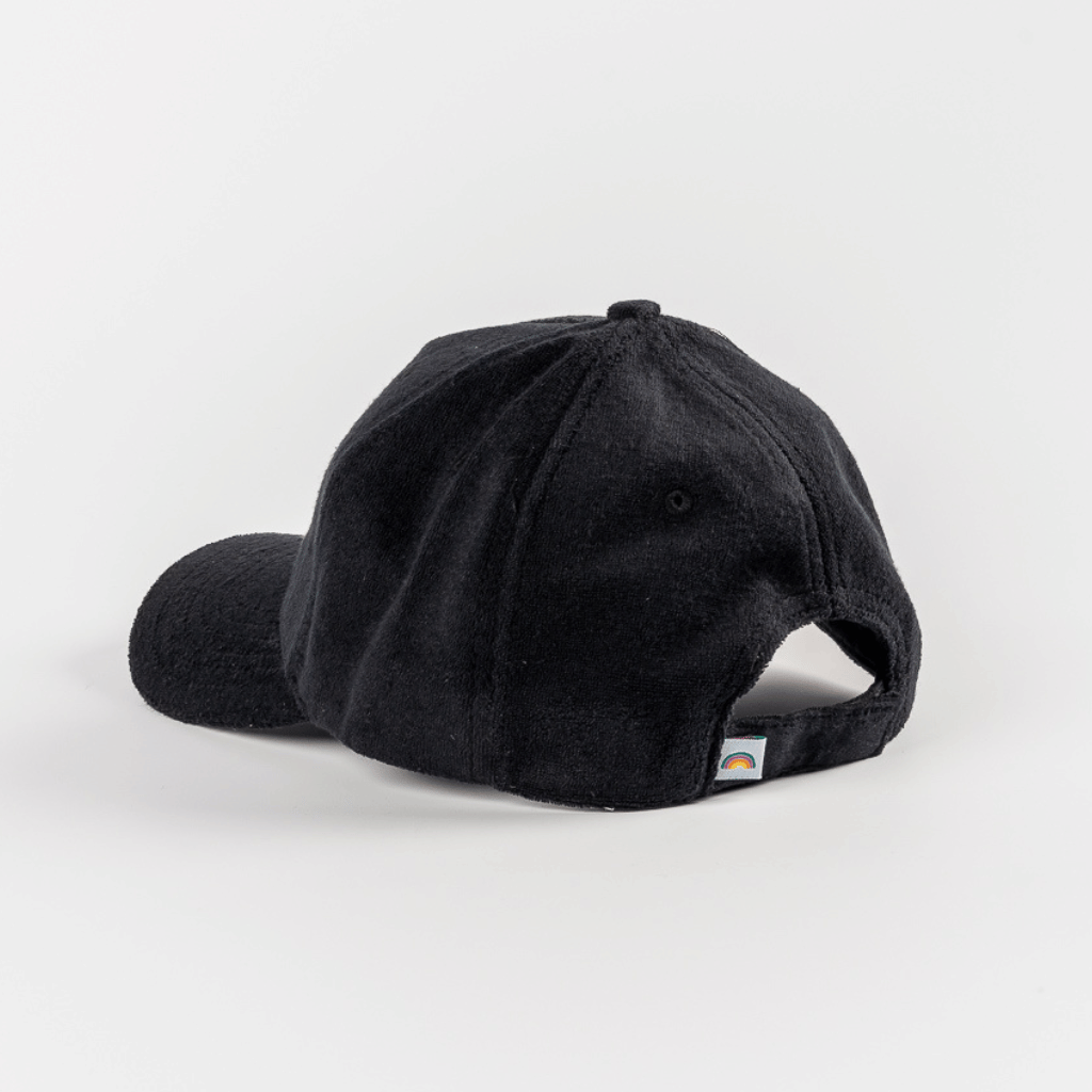 Frottee Cap - All Black mit rückseitigem Klettverschluss und Regenbogen-Tag, seitlich fotografiert, auf weißem Hintergrund.
