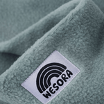 Eltern + Kind Bundle - Fleece Neckwarmer Fresh Mint mit WESORA-Label, Nahaufnahme des weichen, grünlich-grauen Stoffes.