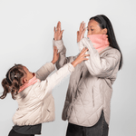 Eltern + Kind Bundle - Fleece Neckwarmer Peachy Rose, getragen von Mutter und Tochter in einem spielerischen Moment, beide mit beige Steppjacken, Hände zum High-Five erhoben.