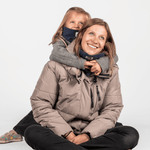 Eltern + Kind Bundle - Fleece Neckwarmer Midnight Blue, getragen von einem Kind, das eine Frau umarmt, beide lächelnd und leicht nach rechts schauend.