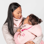 Eltern + Kind Bundle - Fleece Neckwarmer Candy Rose, getragen von Frau und Kind in warmen, rosa Fleece, einander zugewandt, vor hellem Hintergrund.