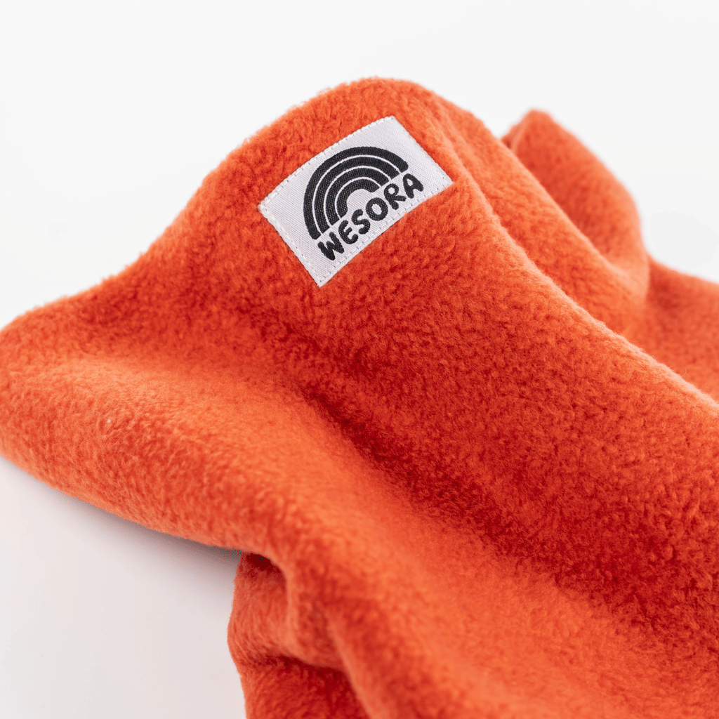 Fleece Neckwarmer - Autumn Nectar mit weichem, leuchtendem Orange und WESORA-Logo, drapiert in lockeren Falten, ideal für kühle Herbstabende.