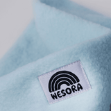 Fleece Neckwarmer - Candy Rose Kid mit blauem, flauschigem Stoff und WESORA-Label, Nahaufnahme. Ideal für Abenteuer im Freien, kuschelig und handgemacht.