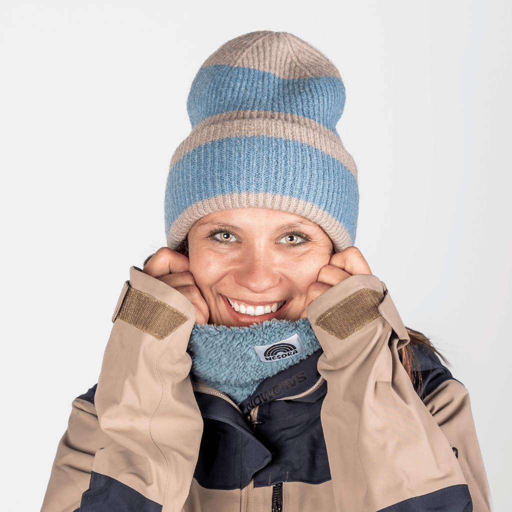 Beanie - Blue Lagon Twist mit Streifenmuster, getragen von junger Frau in Winterkleidung, in Nahaufnahme, lächelnd und kuschelig.