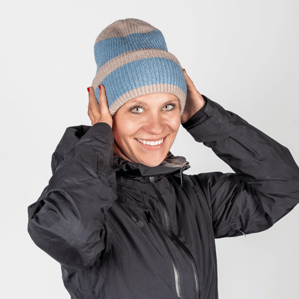 Beanie - Blue Lagon Twist mit geripptem Strickdesign, getragen von einer lächelnden Person, die die Mütze über den Kopf zieht, in schlichtem Hintergrund.