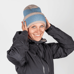 Beanie - Blue Lagon Twist mit geripptem Strickdesign, getragen von einer lächelnden Person, die die Mütze über den Kopf zieht, in schlichtem Hintergrund.