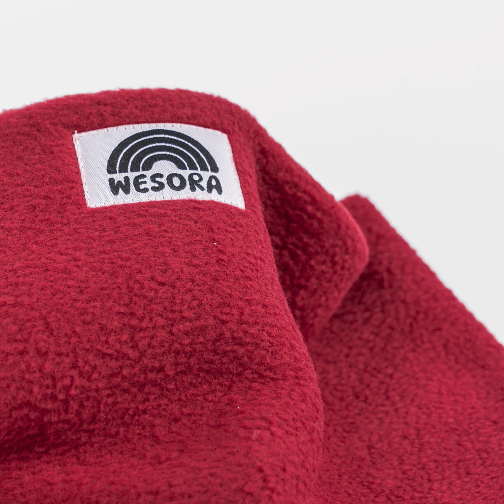 Fleece Neckwarmer - Frosty Bordeaux mit flauschiger Textur und WESORA-Label. Ideal für stilvolle Winterabenteuer. Nahaufnahme des Stoffes.