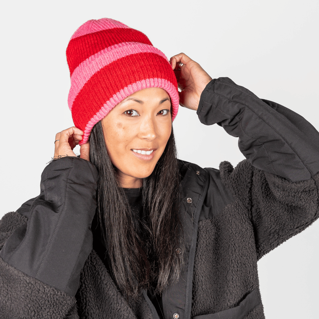 Beanie - Pink Berry Twist mit gestreiftem Strickdesign, getragen von Person mit schwarzer Jacke, frontal fotografiert.