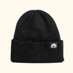 Beanie - All Black mit doppellagigem Rippstrick und breitem Umschlag, verziert mit WESORA-Label, fotografiert aus der Seitenperspektive.