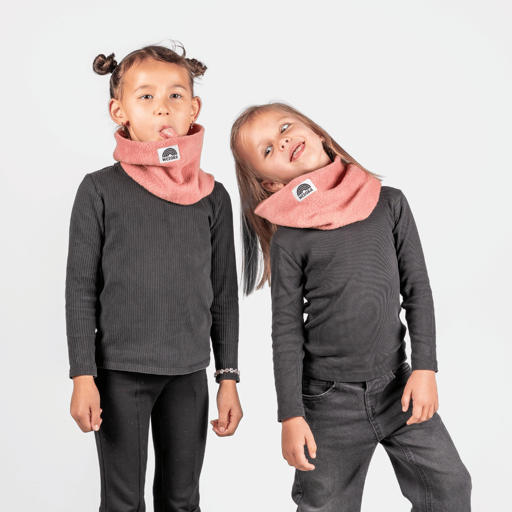 Fleece Neckwarmer - Berry Blossom Kid, getragen von zwei spielerischen Kindern, fotografiert vor einem schlichten Hintergrund, modelliert mit fröhlichen Gesichtern.