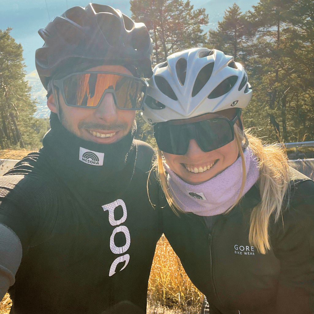 Zwei glückliche Fahrradfahrer machen ein Selfie. Der Mann trägt den Nckwarmer "All Black" ud die Frau den Neckwarmer "Lilac Dreams".