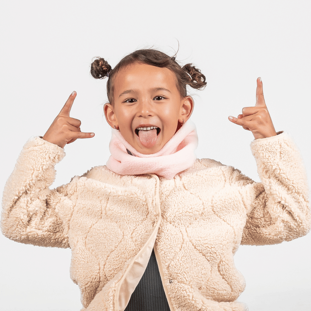 Fleece Neckwarmer - Candy Rose Kid, getragen von einem spielenden Kind mit zwei Buns, das fröhlich in die Kamera blickt und die Rock on-Geste zeigt.