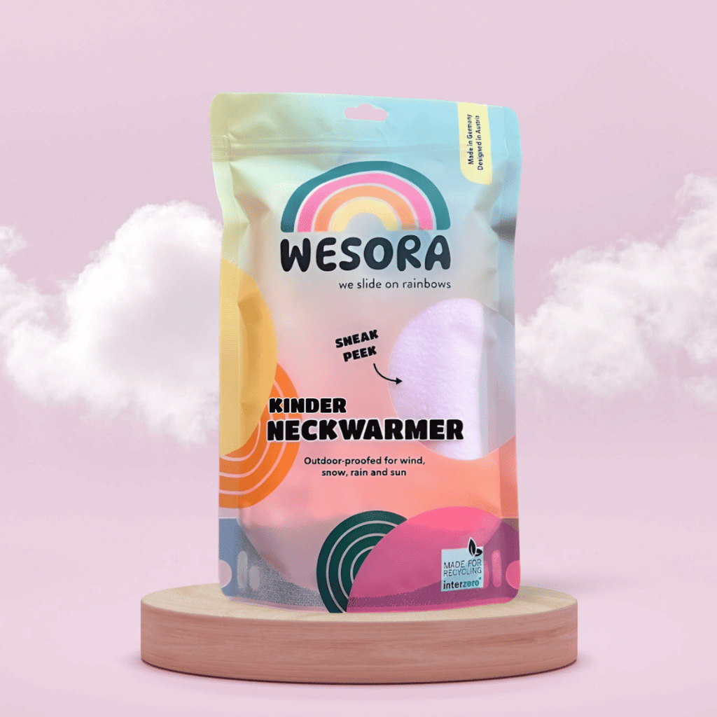 Fleece Neckwarmer - Candy Rose Kid in Verpackung mit Sichtfenster, wetterfest, auf Holzsockel präsentiert. Designed in Österreich, recycelbar. Ideal für Outdoor-Abenteuer.