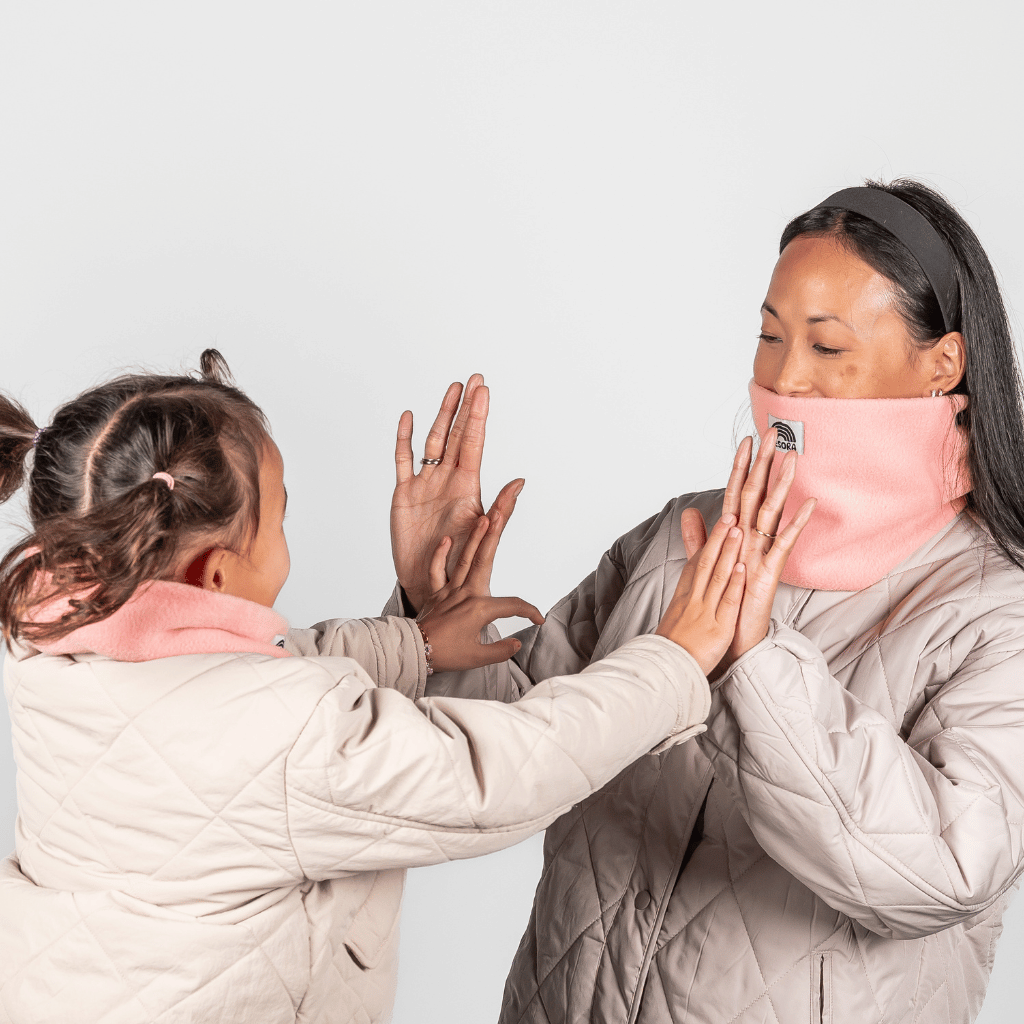 Eltern + Kind Bundle - Fleece Neckwarmer Peachy Rose, getragen von Frau und Mädchen im Spiel, in neutralem Hintergrund.