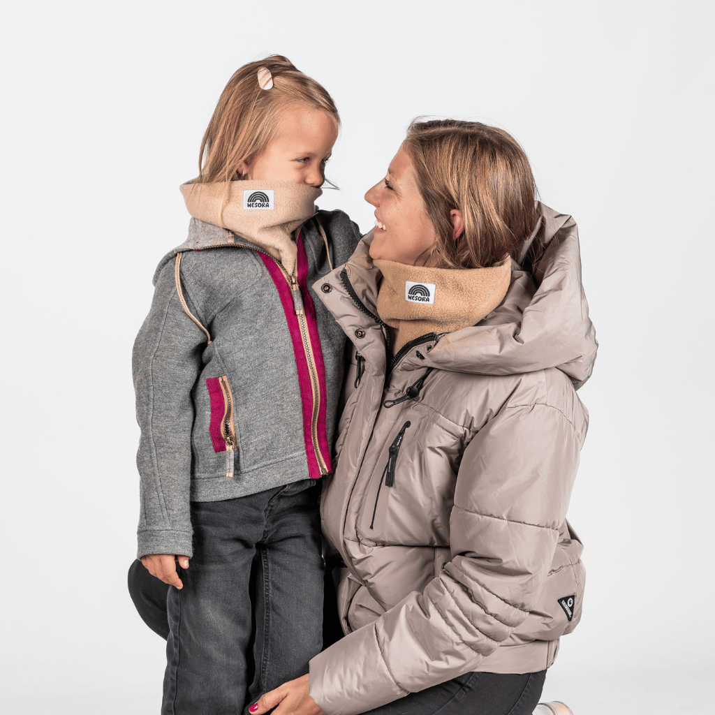 Eltern + Kind Bundle - Fleece Neckwarmer The Teddy, getragen von einer Frau und einem Mädchen in Winterkleidung, lächelnd, auf weißem Hintergrund.