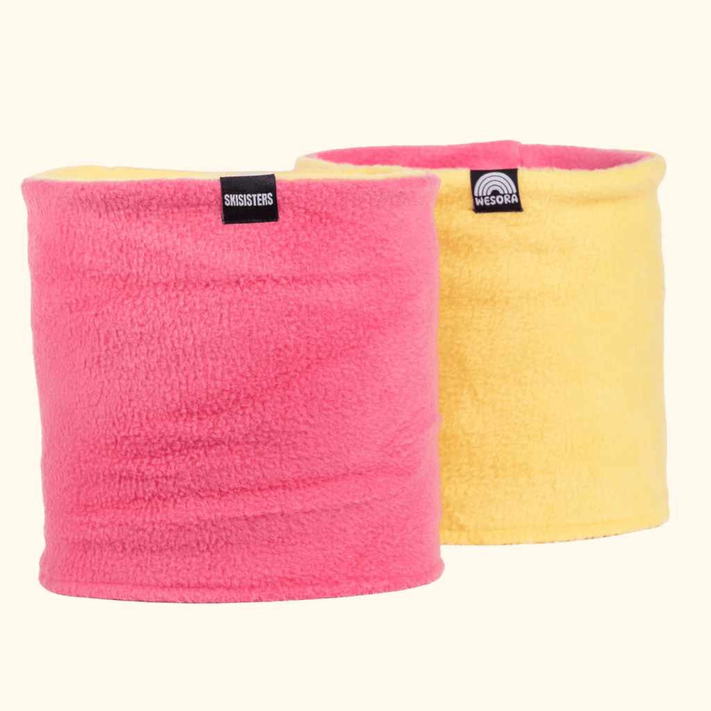Fleece Neckwarmer - Skisister Edition 2, pink und gelb, weiche Röhrenform mit Markenetiketten, ideal für warme Outdoor-Abenteuer, fotografiert in Studioansicht.