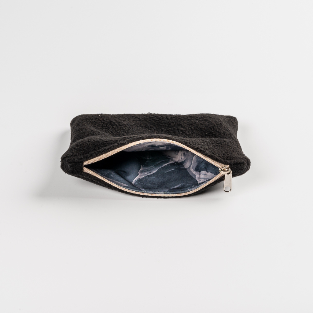 Fleece Zip Bag - All Black mit schwarzem Fleece und gemustertem Innenfutter, teilweise geöffneter Reißverschluss, fotografiert auf weißem Hintergrund.