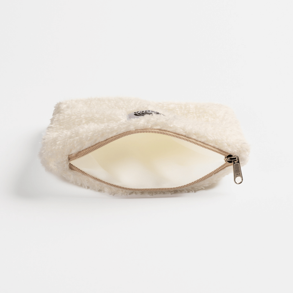Fluffy Zip Bag - White, cremefarbene Kunstfell-Tasche, liegt auf weißem Hintergrund, mit leicht geöffnetem Reißverschluss, zeigt leeres, helles Inneres.