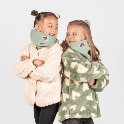 Fleece Neckwarmer - Dreamy Lilac Kid, getragen von zwei lächelnden Kindern in flauschigen Jacken, fotografiert vor einem schlichten Hintergrund, seitlich stehend.