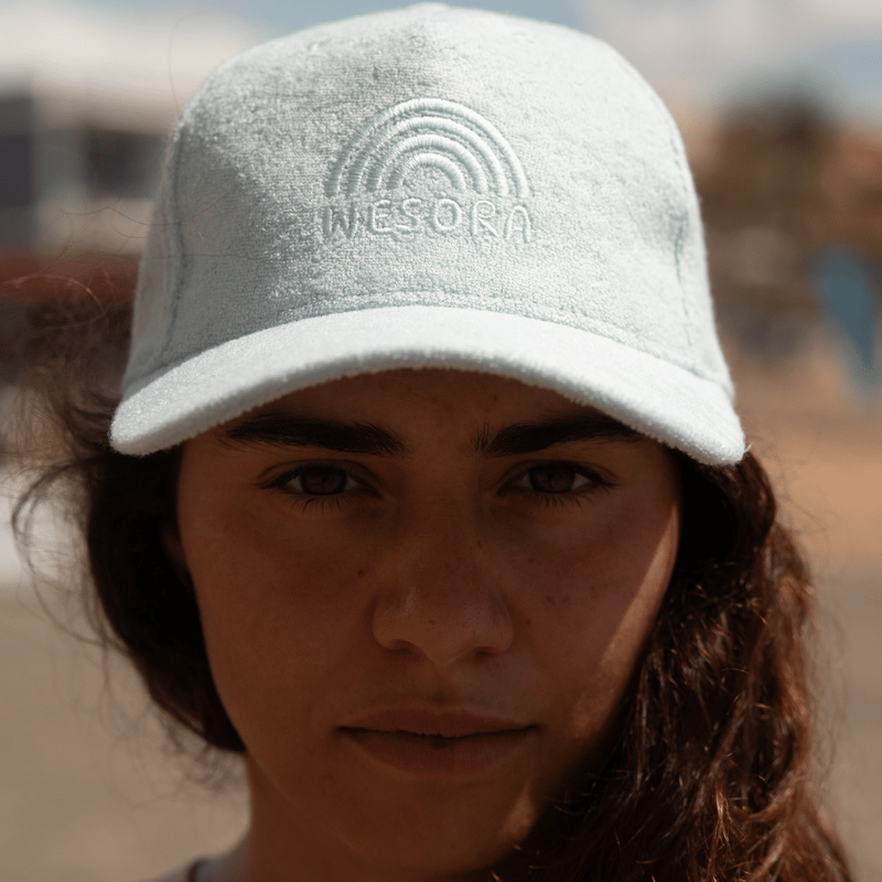 Frottee Cap - Fresh Mint mit Ton-in-Ton Stickerei, getragen von einem Modell am Strand, Blick in die Kamera, betont das praktische Design und den stilvollen Look.