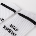 Socken - Hello Sunshine mit schwarzem Streifen am Bündchen und Hello Sunshine-Slogan auf dem Fuß, flach liegend auf hellem Hintergrund.
