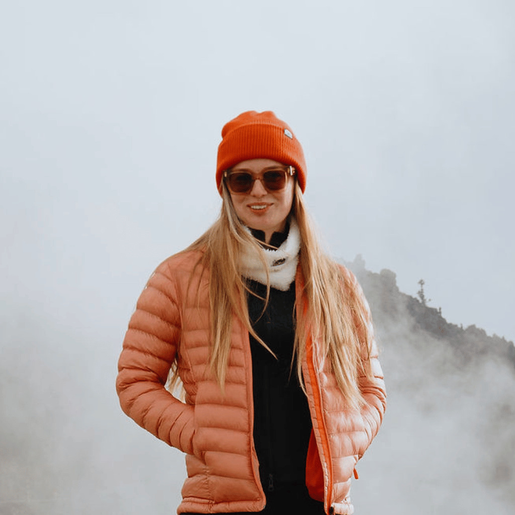 Neckwarmer & Beanie Bundle - Red, getragen von einer Person in nebliger Bergkulisse. Der Beanie leuchtet in kräftigem Rot, der Neckwarmer in sanftem Weiß.