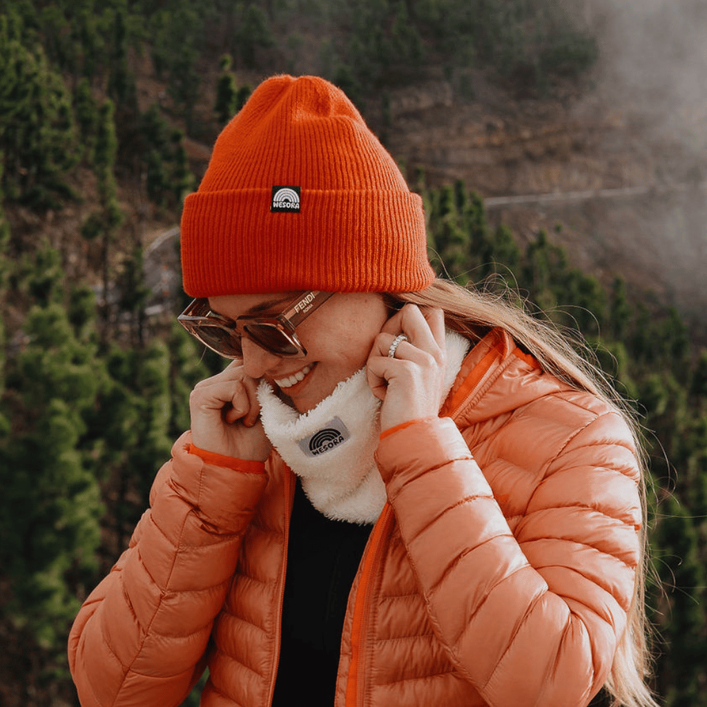 Neckwarmer & Beanie Bundle - Red, getragen von einer Person im Freien, die den weißen Neckwarmer anpasst, ergänzt durch eine orange Beanie.