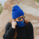 Neckwarmer & Beanie Bundle - Royal, getragen von einer Person vor einem Felsen, mit Sonnenbrille und schwarzem Pullover im Freien fotografiert.