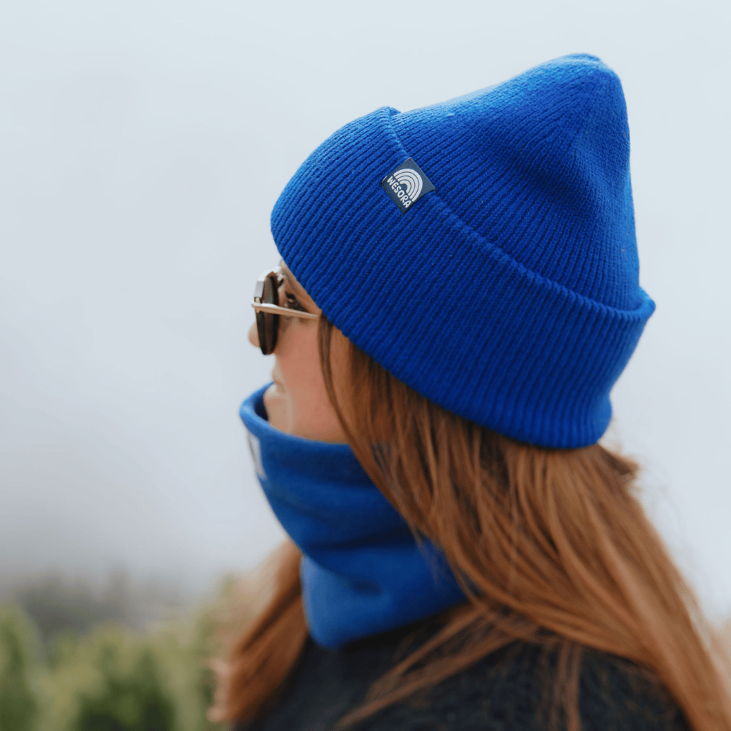 Neckwarmer & Beanie Bundle - Royal, getragen von Person mit Sonnenbrille, Seitenansicht, in nebliger Outdoor-Kulisse.