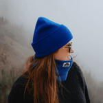 Neckwarmer & Beanie Bundle - Royal, getragen von einer Person im Profil, auf einem nebligen Berghang, blickt lächelnd nach rechts.