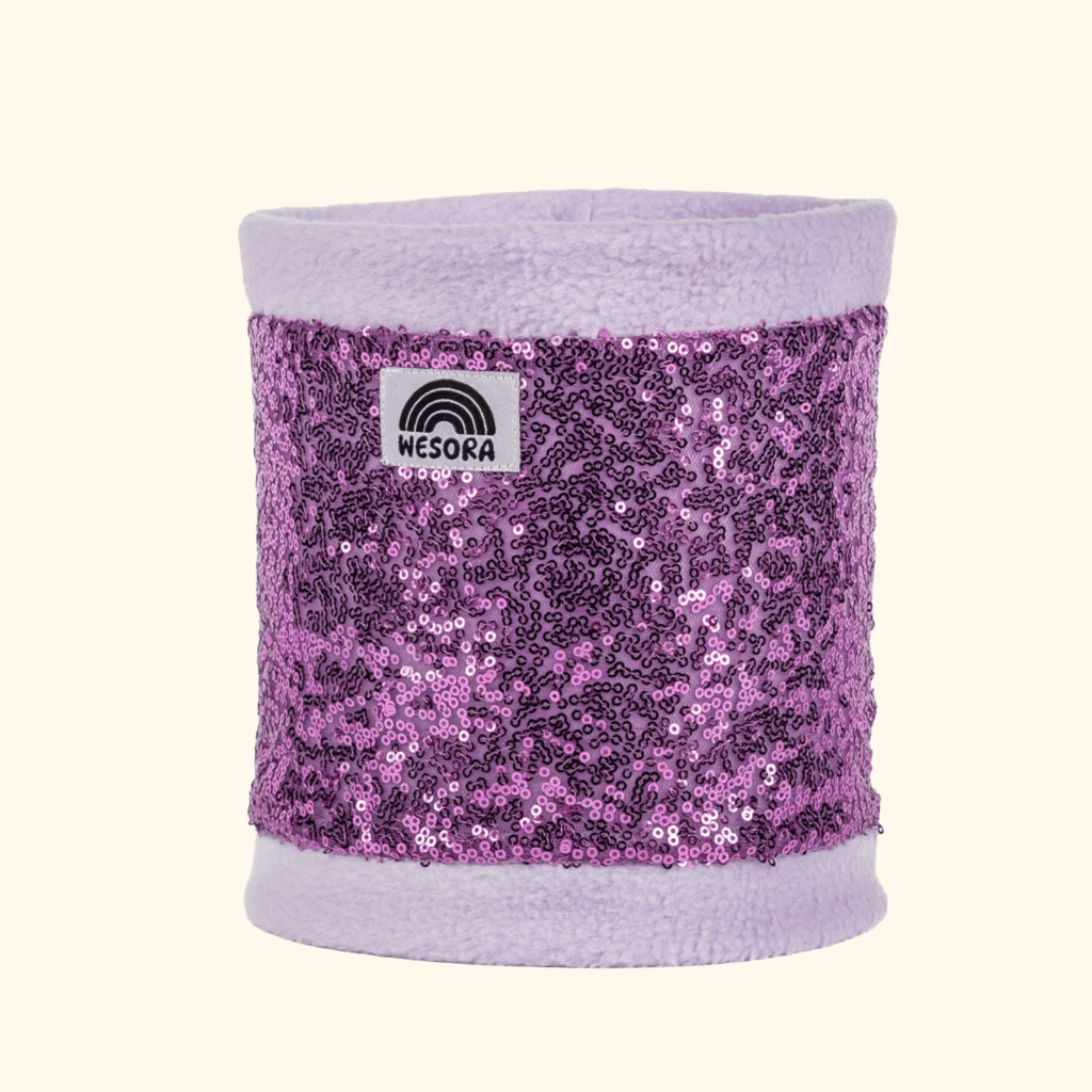 Pailetten Neckwarmer - Sparkle Lilac aus flauschigem Fleece mit glänzenden Pailletten, verziert mit WESORA-Label. Ideal für stilvolle, warme Winterabenteuer.