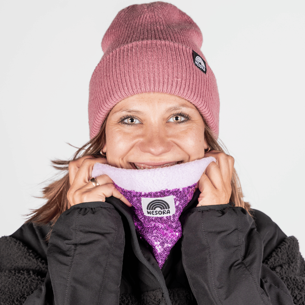Pailetten Neckwarmer - Sparkle Lilac mit glitzerndem Fliederton und Fleecefutter, getragen von einer lächelnden Frau, betont stilvoll gegen Winterkälte.