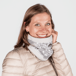 Pailetten Neckwarmer - Sparkle Silver mit schimmernden Details, getragen von einer lächelnden Frau in einem beigen Puffer-Jacke, frontal fotografiert.