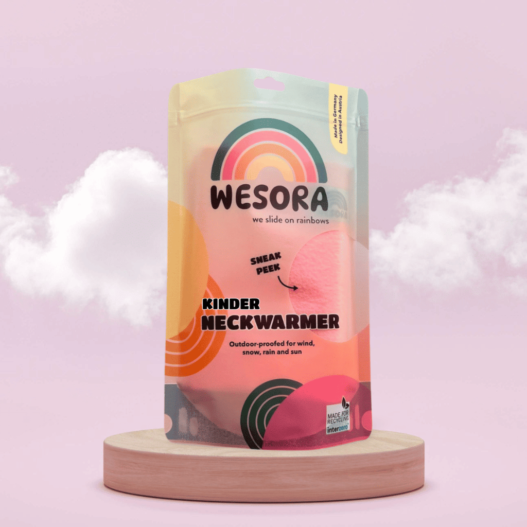 Fleece Neckwarmer - Peachy Rose Kid mit Regenbogenmotiv und Recycling-Label, präsentiert auf Holzpodest, zeigt durch Fenster pinken Fleece-Stoff.