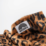 Printed Neckwarmer - Wild Leo Fur mit Leopardenmuster und WESORA-Label, fotografiert auf einer Nahaufnahme, betont wilde Eleganz und handgemachte Qualität.