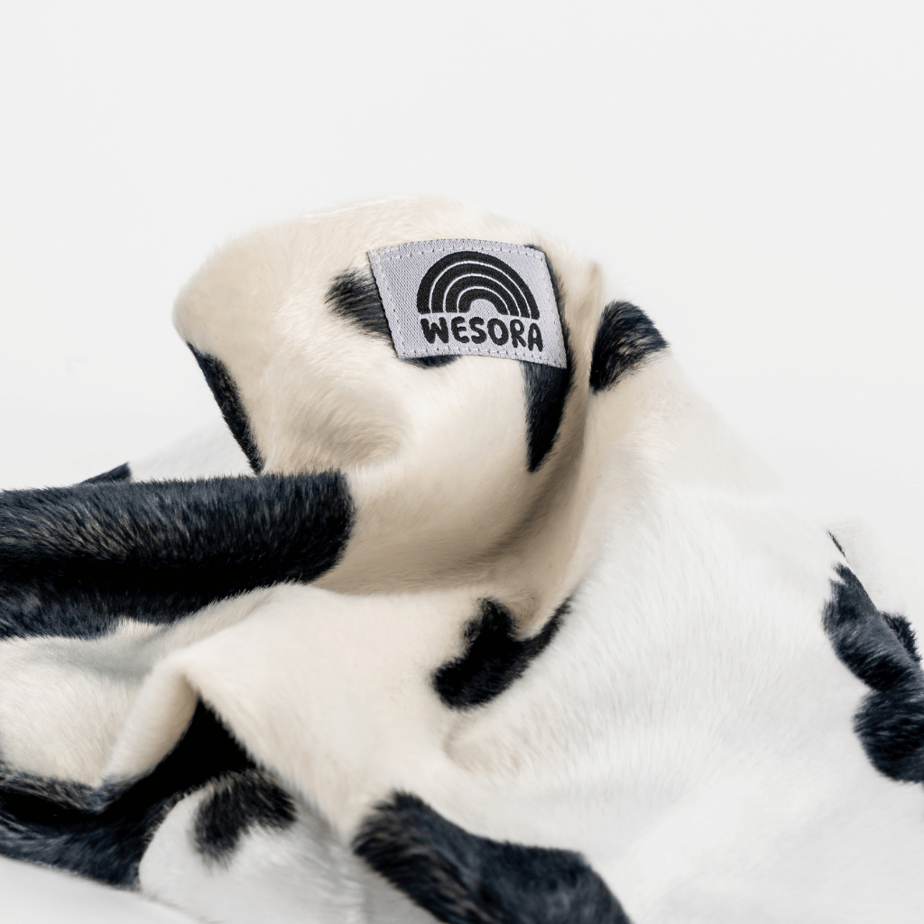 Printed Neckwarmer - Cow Spirit Fur mit Kuhmuster, handgemacht, zeigt das WESORA-Label, ideal für stilvolle Winterabenteuer.