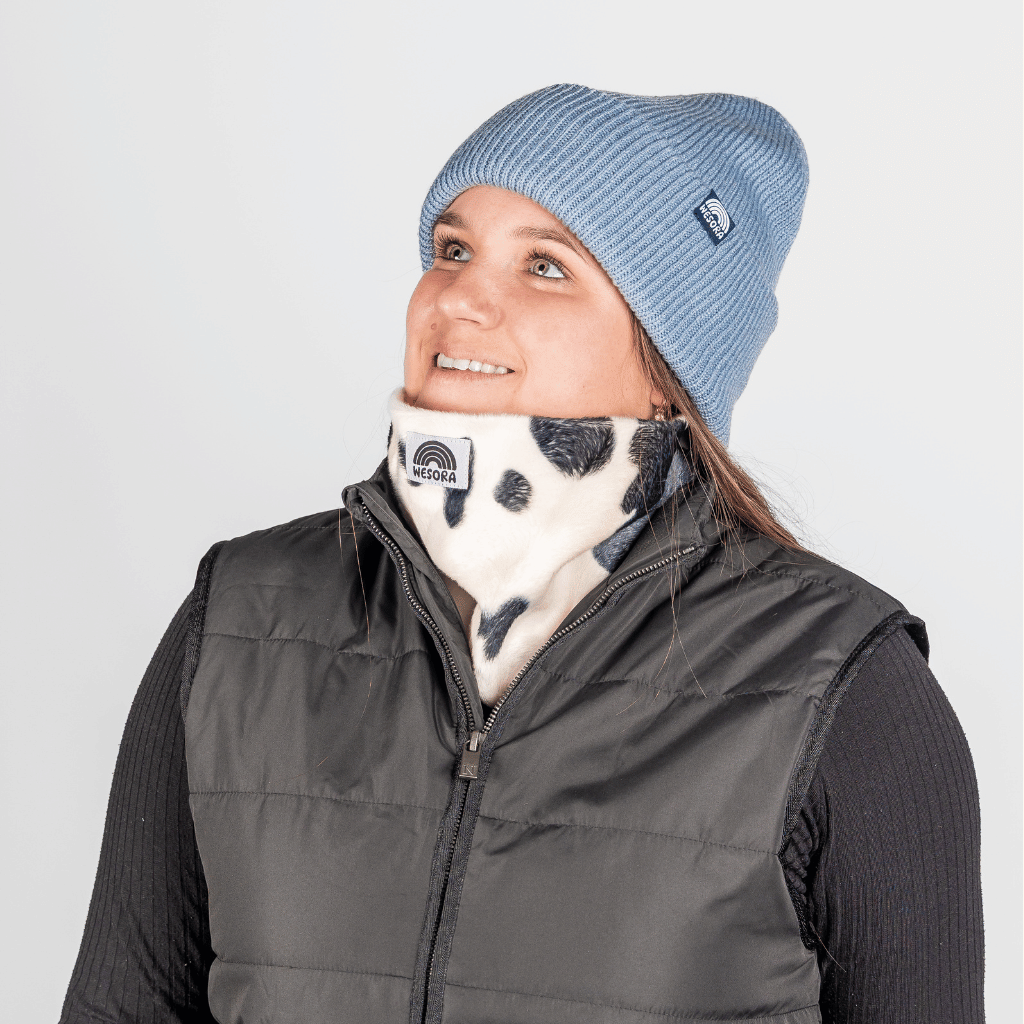 Printed Neckwarmer - Cow Spirit Fur mit Dalmatiner-Muster, getragen von Person im Studio, leicht nach oben blickend und lächelnd.