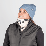 Printed Neckwarmer - Cow Spirit Fur mit Dalmatiner-Muster, getragen von Person im Studio, leicht nach oben blickend und lächelnd.