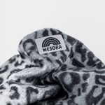 Printed Neckwarmer - Grey Leo Fur mit grauem Leopardenmuster und WESORA-Label, aus weichem Fleece, locker gefaltet fotografiert.