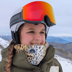 Printed Neckwarmer - Fluffy Wild Leo mit Leopardenmuster, getragen von einer Frau in Winterkleidung, lächelnd auf schneebedecktem Berghang.