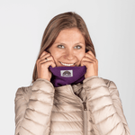 Fleece Neckwarmer - Purple Noir mit semicircle Logo, getragen von einer lächelnden Frau, Studioaufnahme.