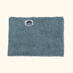 Sherpa Neckwarmer - Fluffy Blue mit weißem Label, fotografiert flach liegend, zeigt stilisiertes Regenbogenmotiv und Markennamen WESORA.