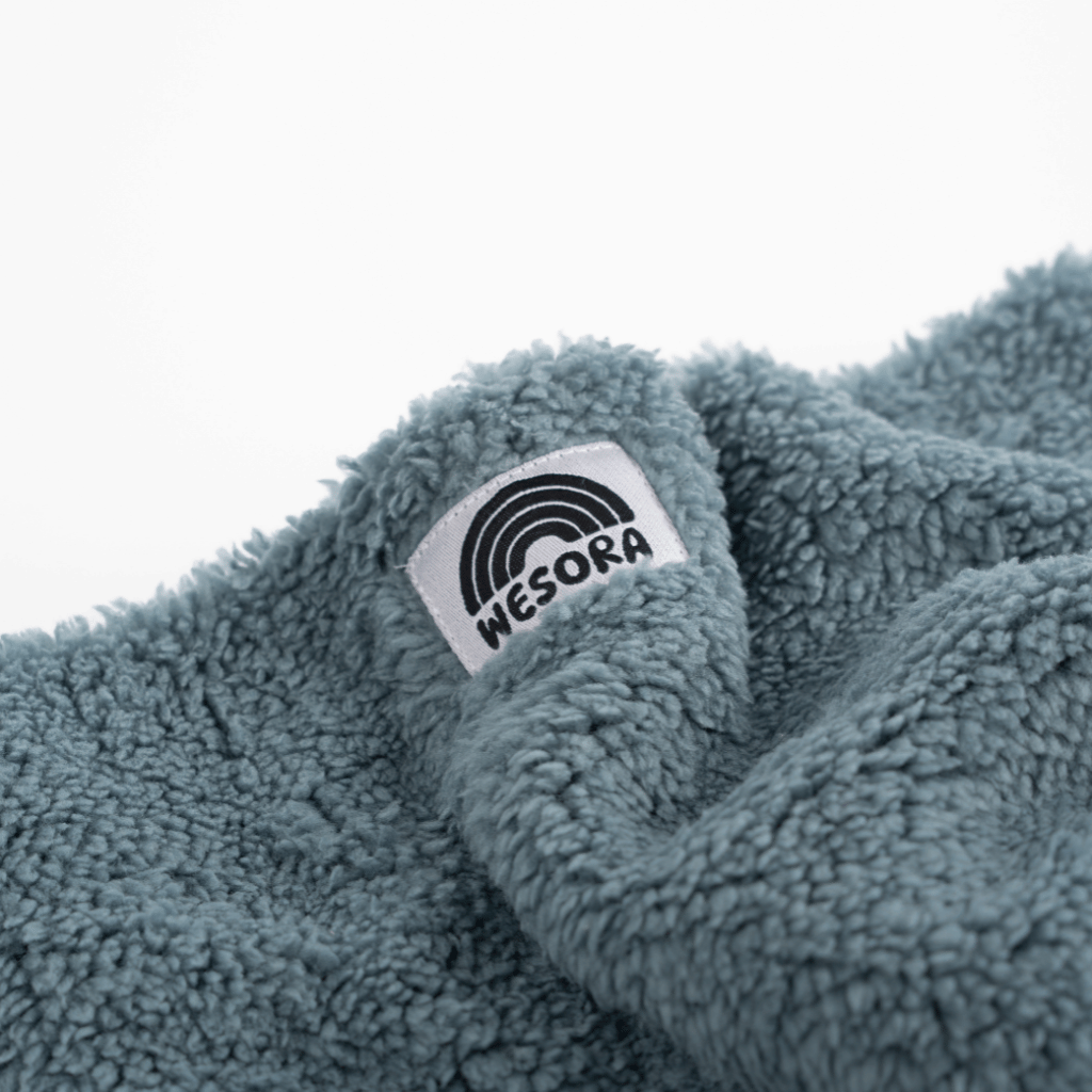 Sherpa Neckwarmer - Fluffy Blue aus weichem, plüschigem Fleece mit WESORA-Label, in Falten drapiert, ideal für warme Winterabenteuer.