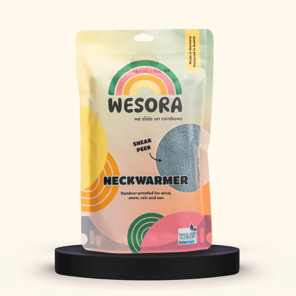 Sherpa Neckwarmer - Fluffy Blue mit flauschigem Fleece im recycelbaren Pastellbeutel, wind- und wetterfest, auf schwarzem Sockel präsentiert.