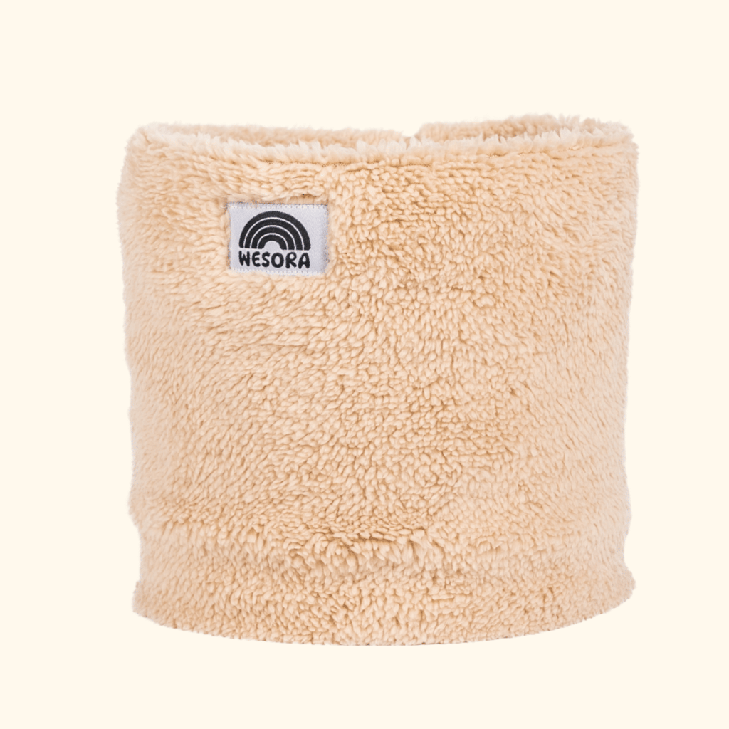 Sherpa Neckwarmer - Fluffy Beige mit WESORA-Label, elegantes beiges Fleece, ideal für gemütliche Winterabenteuer, fotografiert in Nahaufnahme.