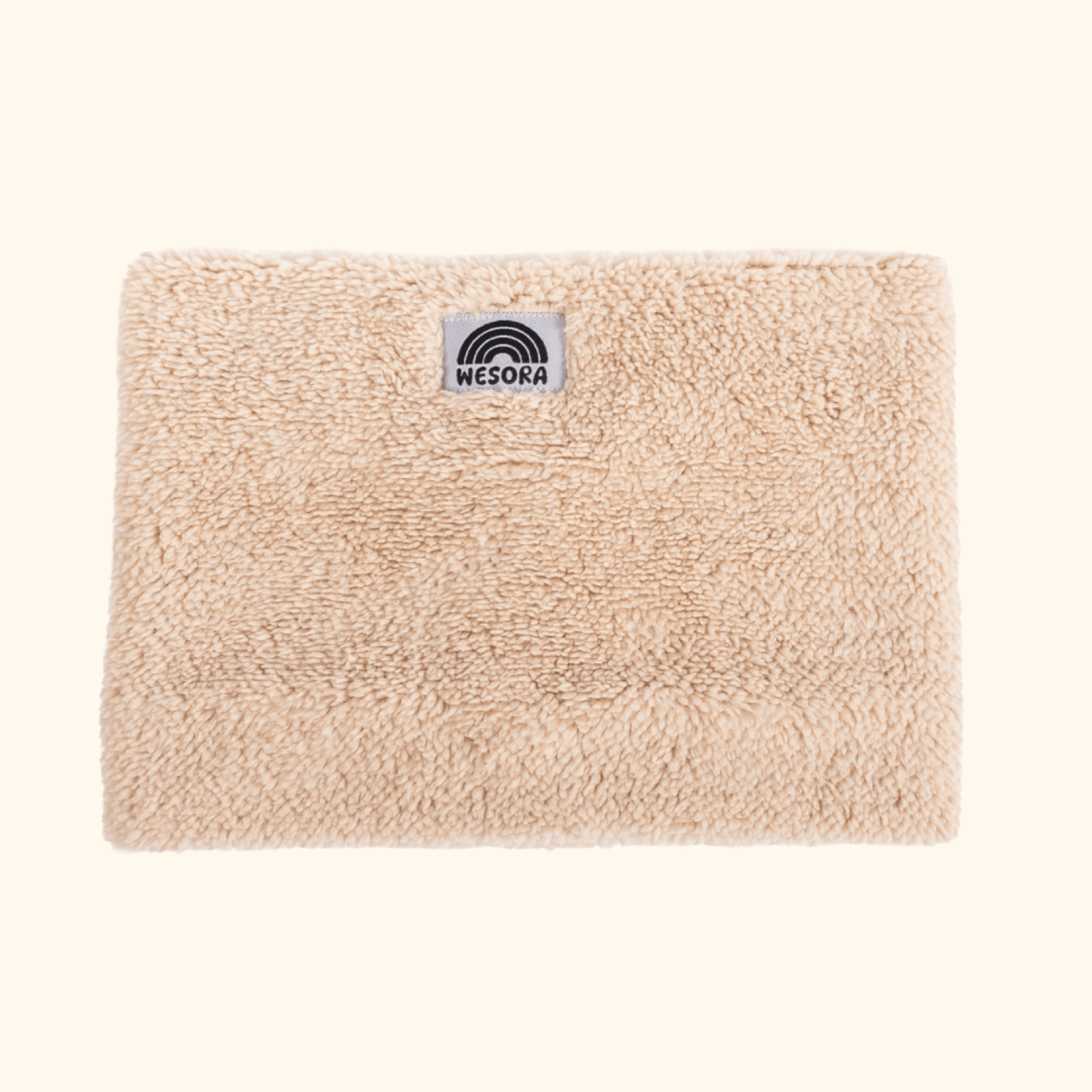 Sherpa Neckwarmer - Fluffy Beige mit flauschigem Fleece und WESORA-Logo, fotografiert in Nahaufnahme. Ideal für stilvolle, warme Wintertage.