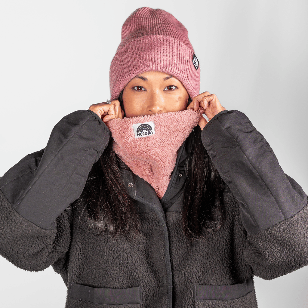 Sherpa Neckwarmer - Fluffy Rose, flauschig und handgemacht, getragen von Person in Winterkleidung, nur Augen sichtbar, in neutralem Setting.