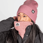 Sherpa Neckwarmer - Fluffy Rose mit WESORA-Logo, getragen von Person in Winterbekleidung, im Profil, Hand am Hinterkopf.