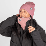 Sherpa Neckwarmer - Fluffy Rose, getragen von einer lächelnden Person, die das rosa Accessoire anpasst, fotografiert in einem Studio.